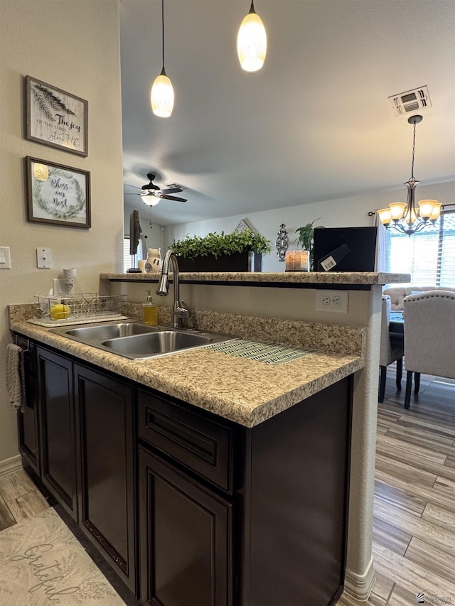 kitchen with sink, decorative light fixtures, light hardwood / wood-style flooring, and ceiling fan with notable chandelier