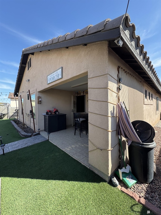 view of side of home with a patio area and a lawn