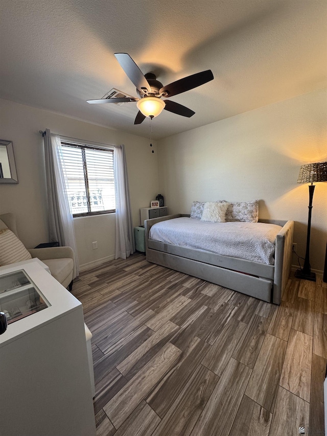 bedroom with dark hardwood / wood-style floors, a textured ceiling, and ceiling fan