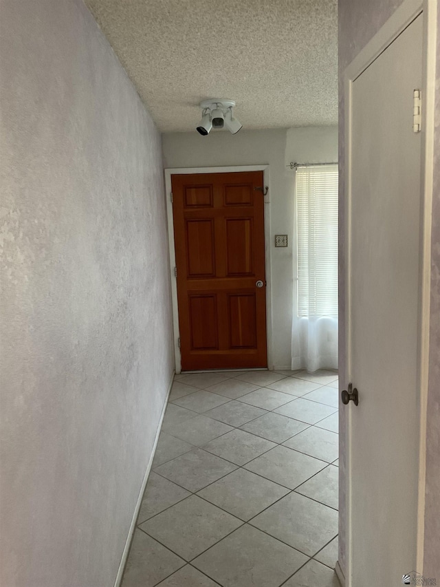 corridor featuring a textured ceiling and light tile patterned floors