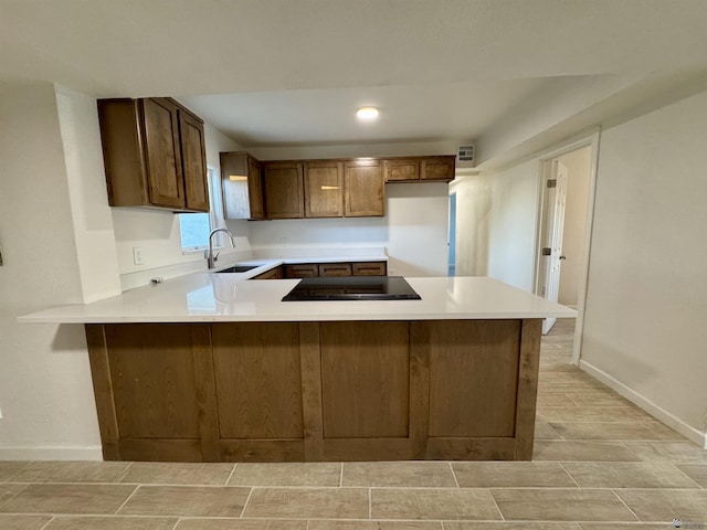 kitchen featuring kitchen peninsula, black electric stovetop, and sink