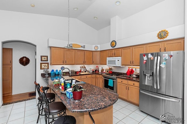 10243 Fairway Loop, Yuma, AZ 85367 - kitchen with appliances with stainless steel finishes, high vaulted ceiling, light tile patterned floors, arched walkways, and a kitchen breakfast bar