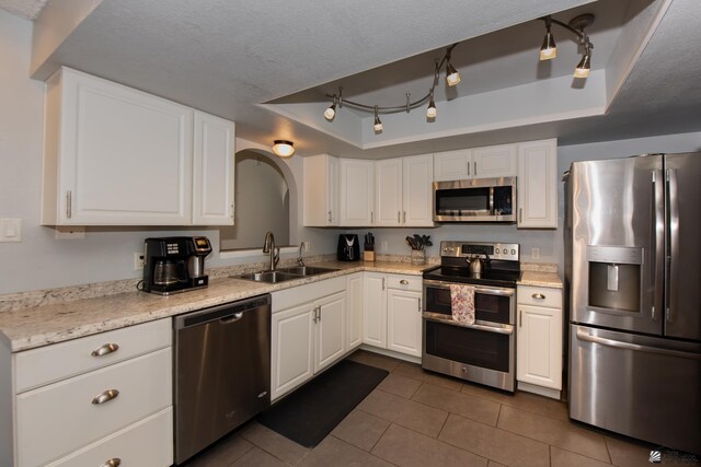 660 E 26th St, Yuma, AZ 85365 - kitchen with appliances with stainless steel finishes, a sink, a tray ceiling, dark tile patterned flooring, and arched walkways