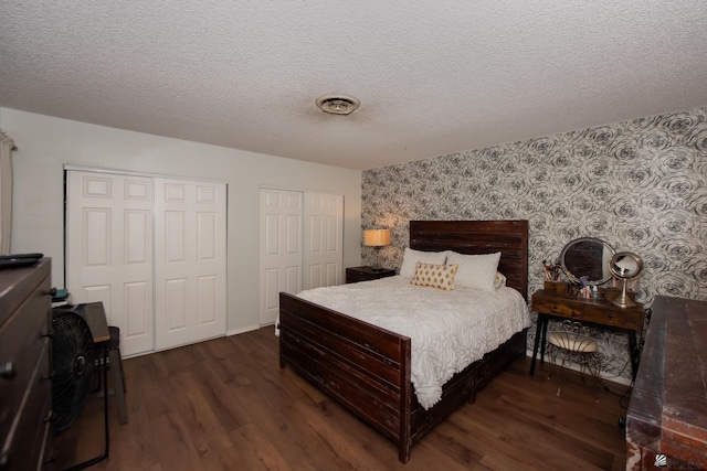 660 E 26th St, Yuma, AZ 85365 - bedroom with wallpapered walls, an accent wall, two closets, dark wood-style flooring, and a textured ceiling