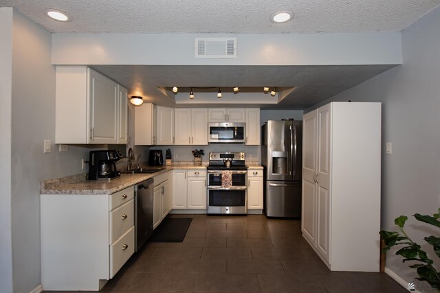 660 E 26th St, Yuma, AZ 85365 - kitchen with appliances with stainless steel finishes, a sink, a tray ceiling, a textured ceiling, and white cabinetry