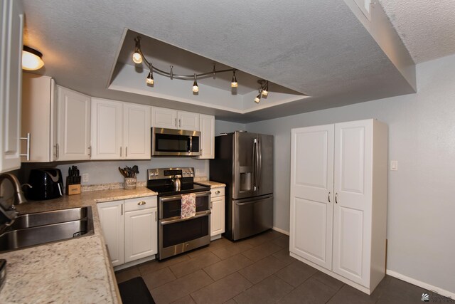 660 E 26th St, Yuma, AZ 85365 - kitchen with appliances with stainless steel finishes, a raised ceiling, a sink, white cabinetry, and a textured ceiling