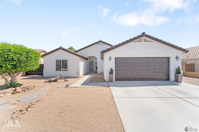 ranch-style house featuring a garage, fence, stucco siding, concrete driveway, and a tile roof