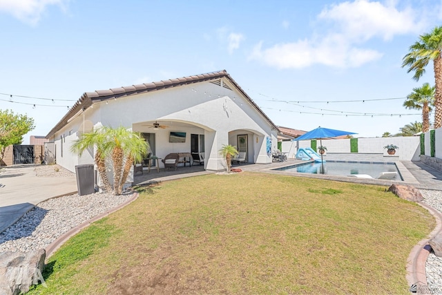 rear view of property with ceiling fan, a patio area, a fenced backyard, a yard, and stucco siding