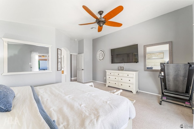 carpeted bedroom with arched walkways, baseboards, visible vents, and ceiling fan