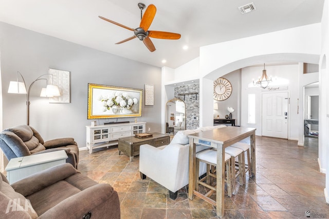 living room with visible vents, arched walkways, ceiling fan, and stone tile floors