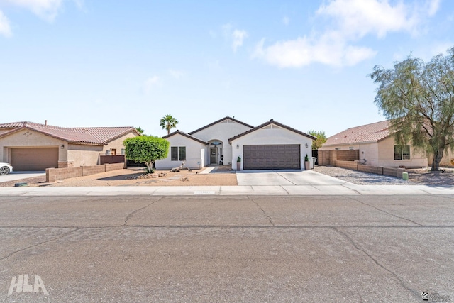 single story home featuring a tiled roof, fence, concrete driveway, an attached garage, and stucco siding