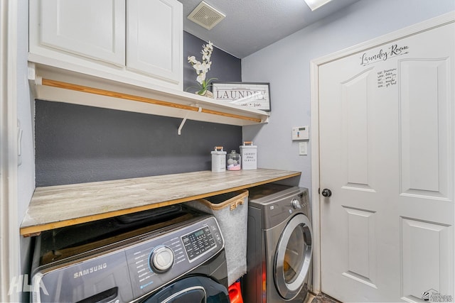 washroom featuring separate washer and dryer, cabinet space, and visible vents