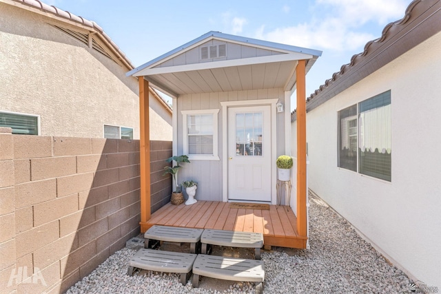 doorway to property featuring fence and stucco siding
