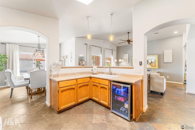 kitchen featuring ceiling fan, a sink, light countertops, arched walkways, and wine cooler