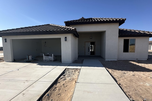 10864 E 45th St, Yuma, AZ 85367 - back of house with concrete driveway, a garage, stucco siding, a tiled roof, and a patio area