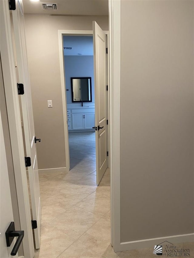 corridor featuring sink and light tile patterned flooring