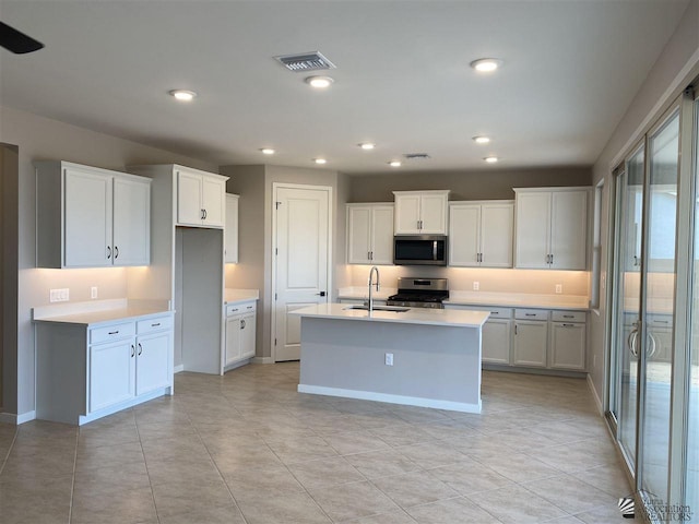 kitchen featuring white cabinets, appliances with stainless steel finishes, a center island with sink, and sink