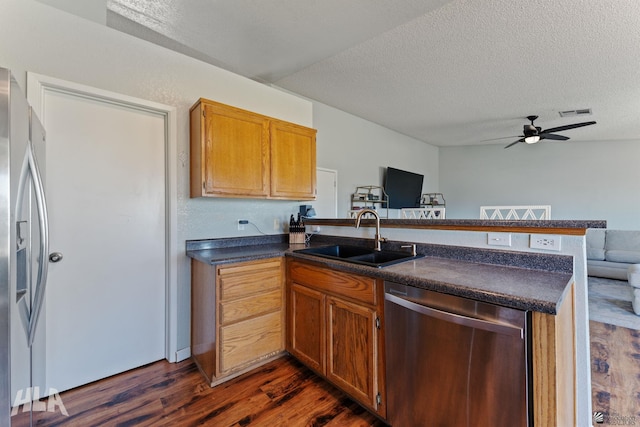 6248 E 42nd Ln, Yuma, AZ 85365 - kitchen with stainless steel appliances, a peninsula, dark countertops, dark wood-style flooring, and a textured ceiling