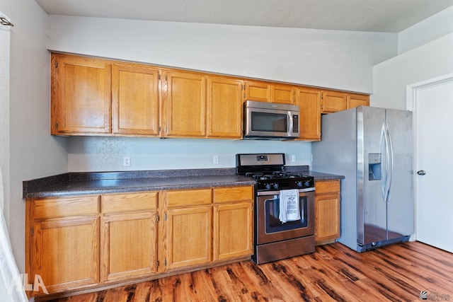 6248 E 42nd Ln, Yuma, AZ 85365 - kitchen featuring appliances with stainless steel finishes, dark countertops, wood finished floors, and brown cabinets