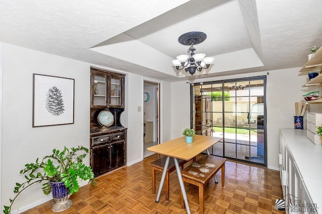 dining space featuring baseboards, a tray ceiling, a textured ceiling, and a notable chandelier
