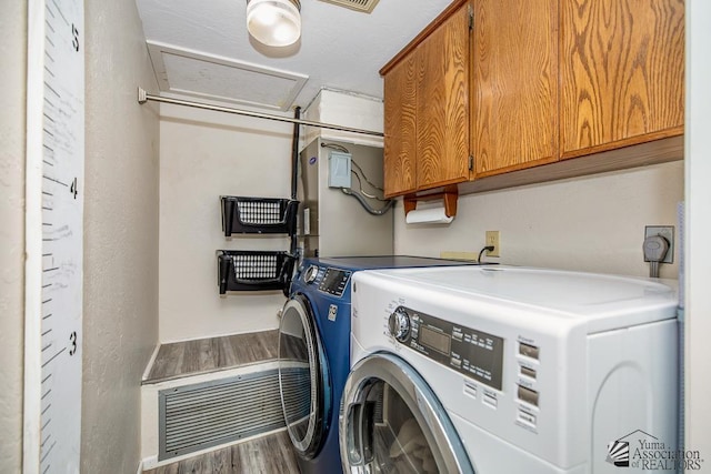 laundry room with cabinet space, separate washer and dryer, visible vents, and wood finished floors