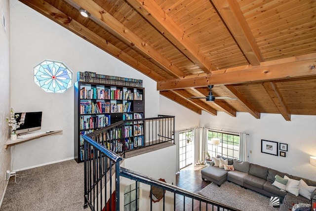 carpeted living area featuring ceiling fan, baseboards, lofted ceiling with beams, and wood ceiling