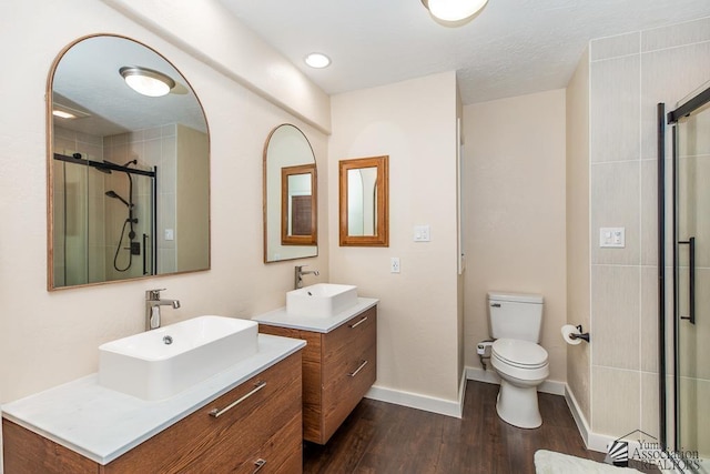 bathroom with a sink, baseboards, a stall shower, and wood finished floors