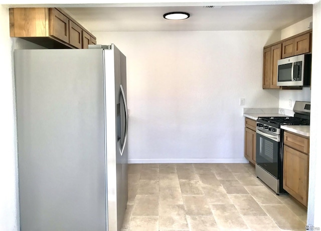 275 E 26th St, Yuma, AZ 85364 - kitchen featuring light countertops, brown cabinets, baseboards, and appliances with stainless steel finishes