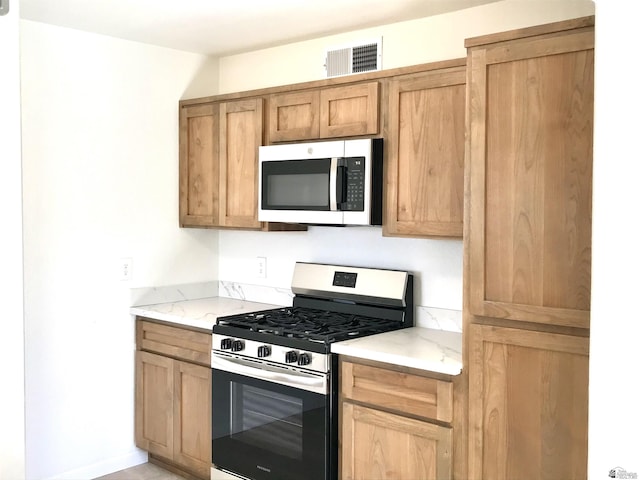 275 E 26th St, Yuma, AZ 85364 - kitchen with light stone countertops, appliances with stainless steel finishes, baseboards, and visible vents
