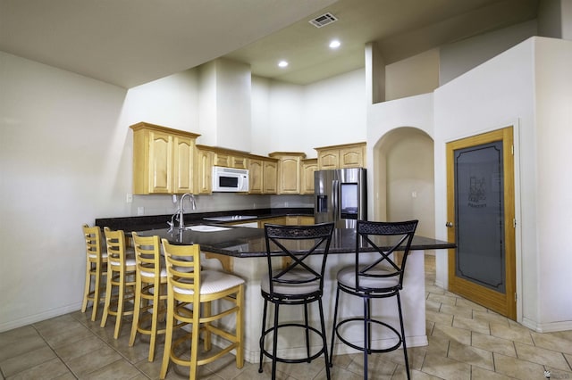 14158 E 49th Dr, Yuma, AZ 85367 - kitchen featuring stainless steel fridge with ice dispenser, baseboards, white microwave, a peninsula, and a high ceiling