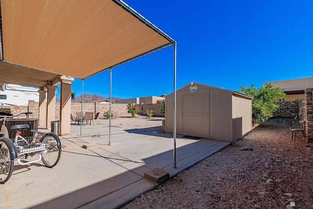 14307 E 49th Ln, Yuma, AZ 85367 - view of patio featuring a fenced backyard, a mountain view, an outdoor structure, and a shed