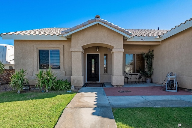 14307 E 49th Ln, Yuma, AZ 85367 - property entrance with a lawn, a patio, a tile roof, and stucco siding