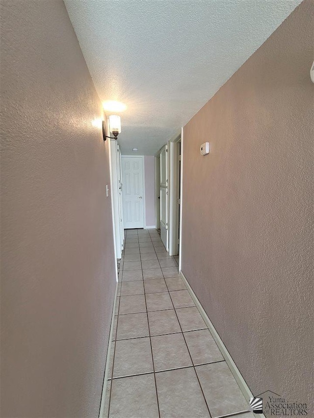 2082 E Ln Mesa St, Yuma, AZ 85365 - hall with light tile patterned floors, baseboards, a textured wall, and a textured ceiling