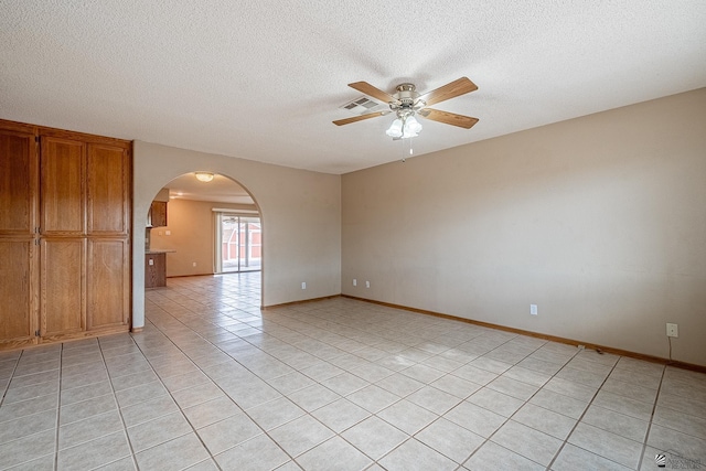 spare room with ceiling fan, a textured ceiling, visible vents, arched walkways, and light tile patterned floors