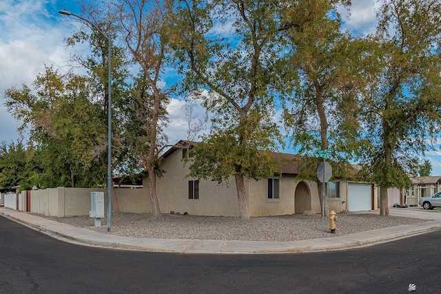 view of front of house featuring stucco siding, fence, driveway, and a garage