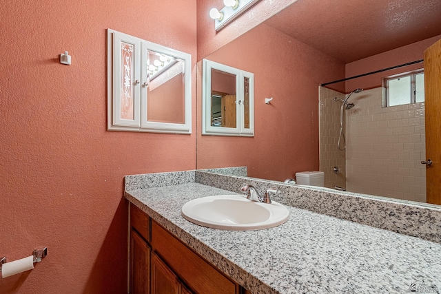 bathroom with vanity, a textured wall, and toilet