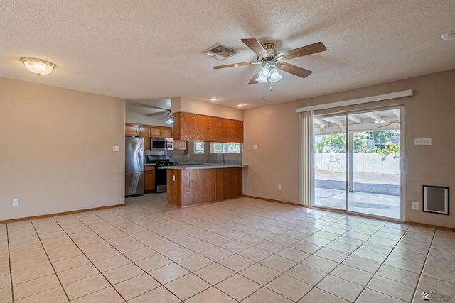 kitchen with brown cabinets, appliances with stainless steel finishes, a textured ceiling, a peninsula, and visible vents