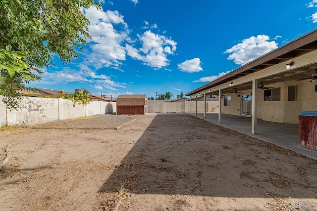 view of yard with an outdoor structure, ceiling fan, a patio, a fenced backyard, and a shed