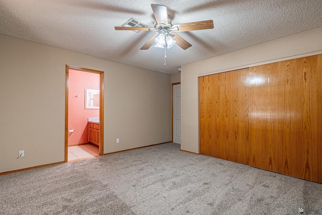 unfurnished bedroom featuring carpet floors, a closet, a textured ceiling, and connected bathroom