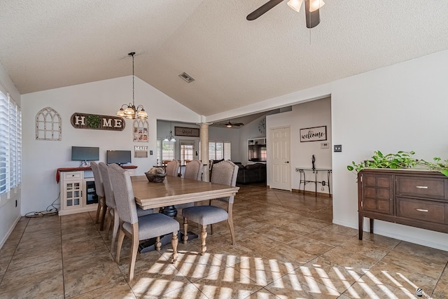 dining space featuring lofted ceiling, ceiling fan with notable chandelier, decorative columns, and a textured ceiling