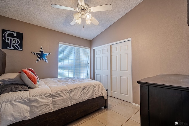 bedroom featuring lofted ceiling, light tile patterned floors, a textured ceiling, and a closet