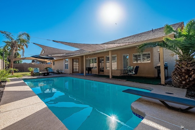 view of swimming pool featuring area for grilling and a diving board