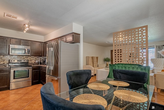 kitchen featuring stainless steel appliances, dark brown cabinetry, visible vents, and open floor plan