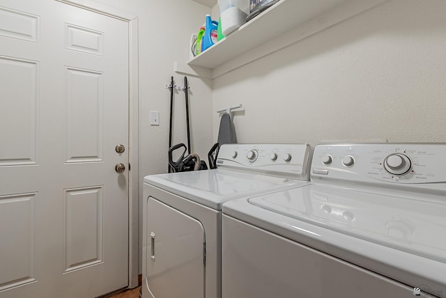 washroom featuring laundry area, a textured wall, and separate washer and dryer