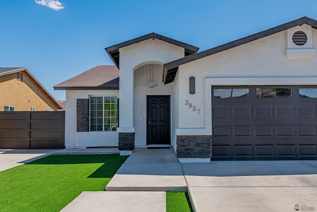 single story home with a front yard, concrete driveway, an attached garage, stone siding, and stucco siding