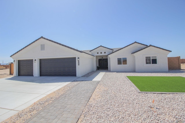 view of front of house featuring fence, an attached garage, driveway, and stucco siding