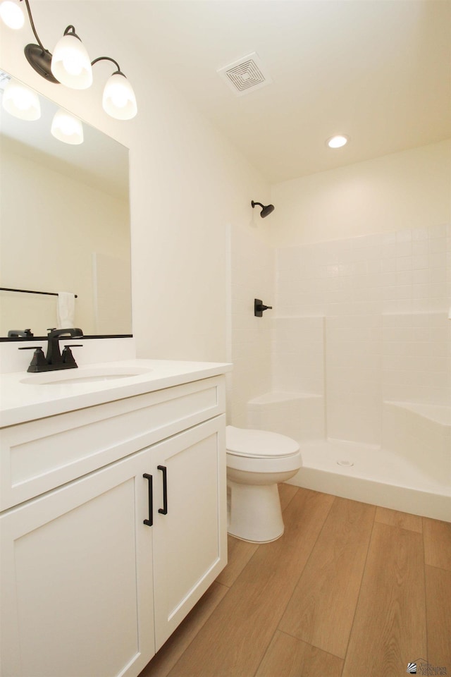 bathroom with toilet, visible vents, wood finished floors, and a shower