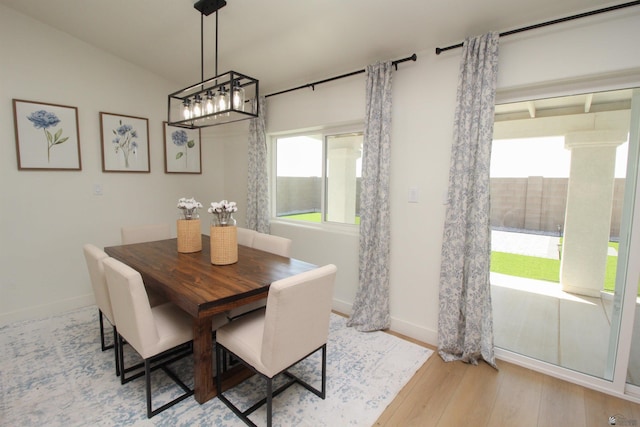 dining room with baseboards, wood finished floors, and an inviting chandelier