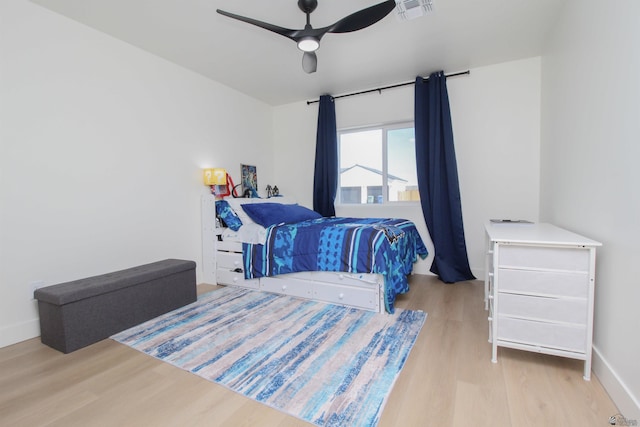 bedroom featuring baseboards, ceiling fan, visible vents, and wood finished floors