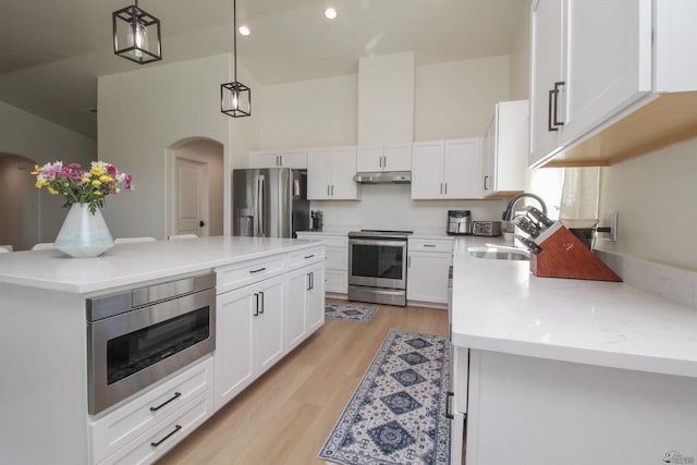 kitchen featuring a sink, arched walkways, stainless steel appliances, white cabinetry, and under cabinet range hood